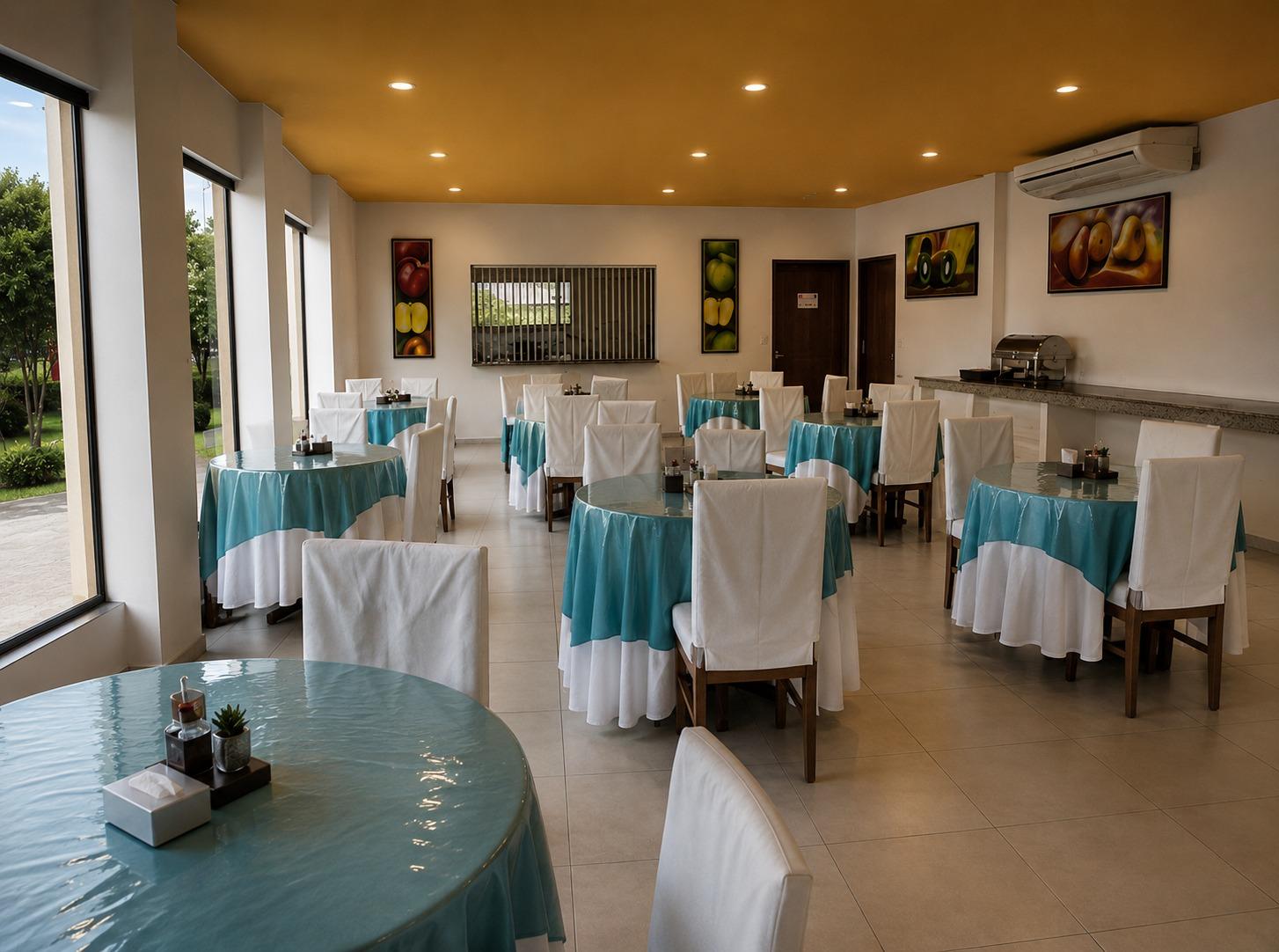 Salão do café da manhã do Hotel Flor da Mata com mesas redondas, toalhas azuis e cadeiras com capa branca