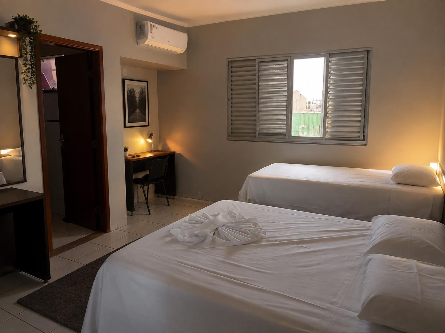 Quarto do Hotel Flor da Mata com duas camas de solteiro, ar-condicionado, escrivaninha e iluminação suave